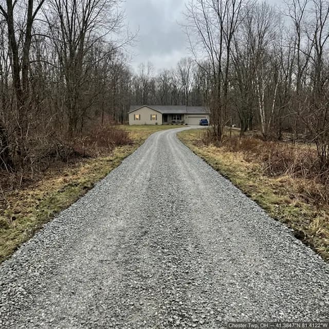 The same Chester Township, Ohio gravel driveway after restoration — an even, gently crowned stone surface running clear from the road to the house