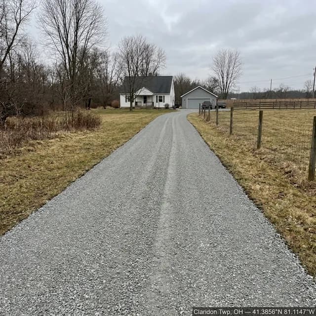 The same Claridon Township, Ohio driveway after restoration — clean, evenly covered gravel with a defined edge, leading up to the farmhouse