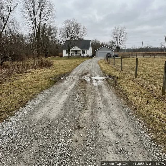 Worn gravel driveway in Claridon Township, Ohio before restoration — thin, patchy stone with bare spots opening up down the center of the drive