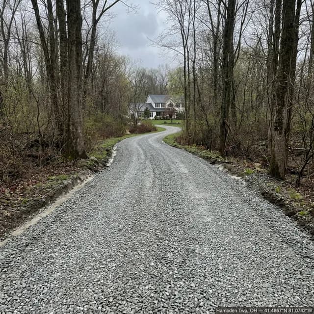 The same curving Hambden Township, Ohio driveway after restoration — a firm, crowned gravel surface with cut-back shoulders carrying water off the drive